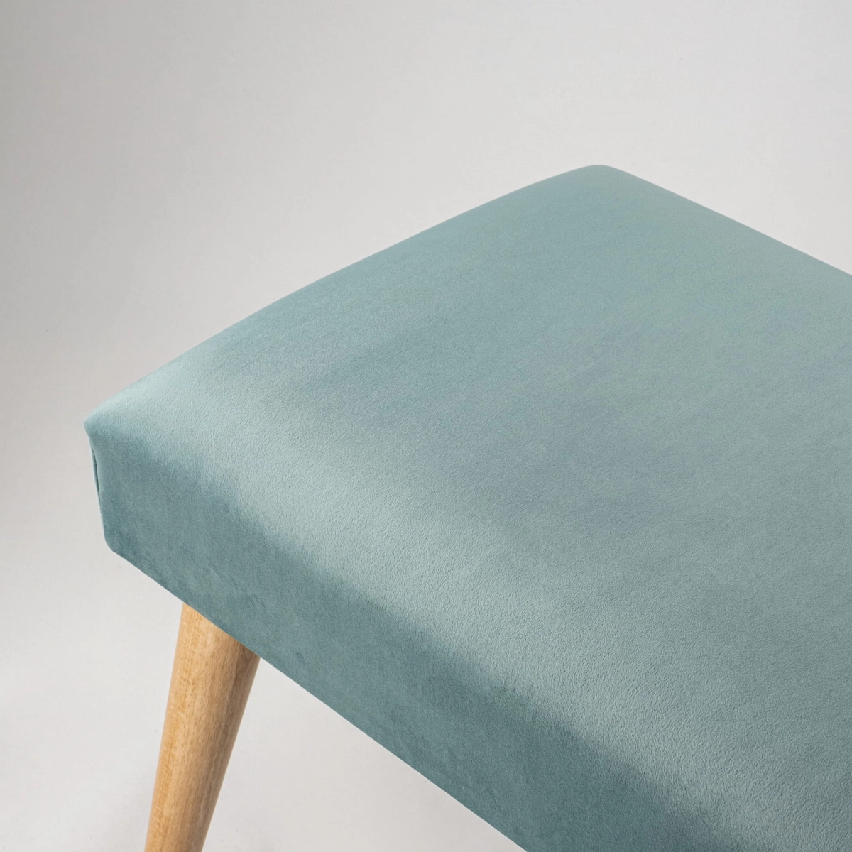 Elegante panca imbottita color menta con gambe in legno