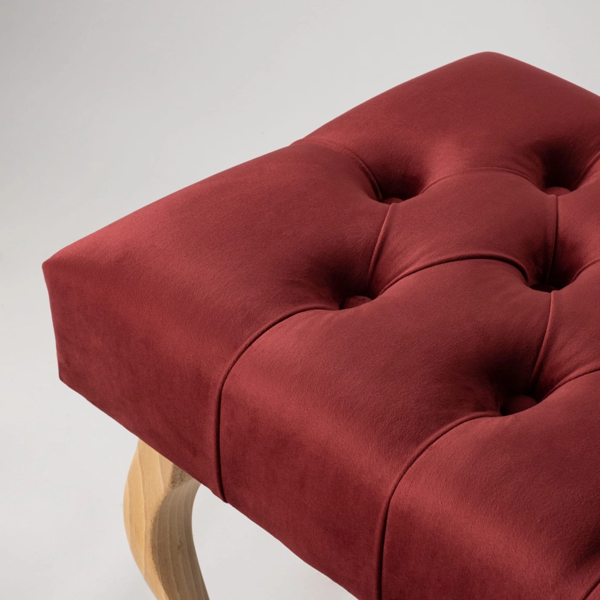 Elegante panca imbottita in un intenso bordeaux con gambe in legno
